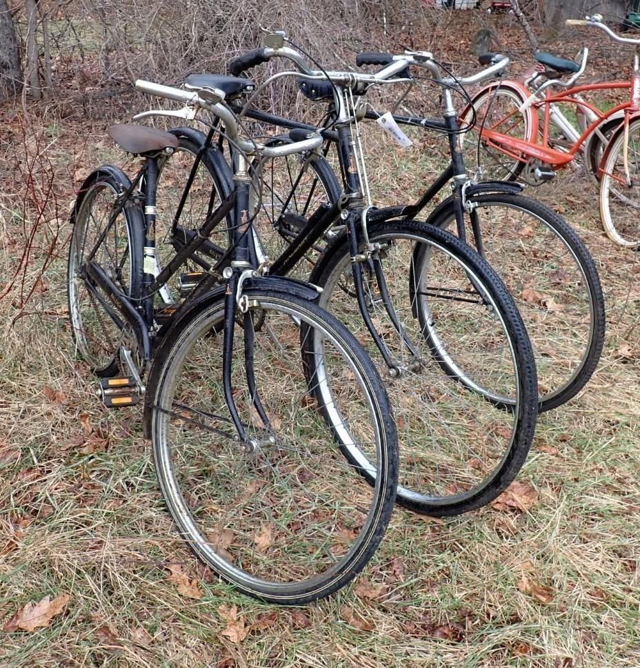 Three black vintage-style bicycles parked on grass.