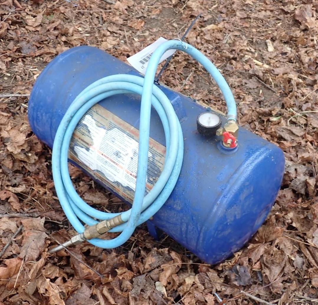 A blue portable air tank with a coiled blue hose and a pressure gauge.