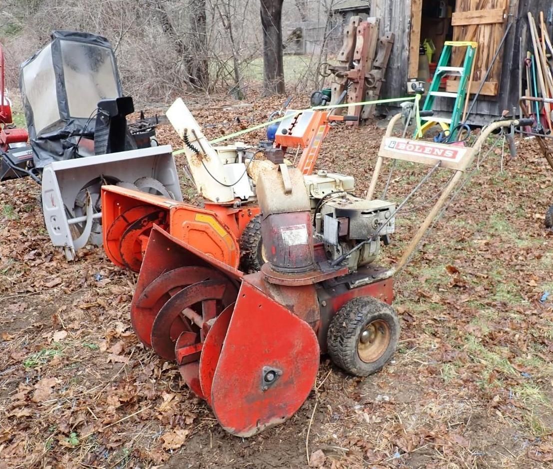 Three snowblowers parked outdoors.