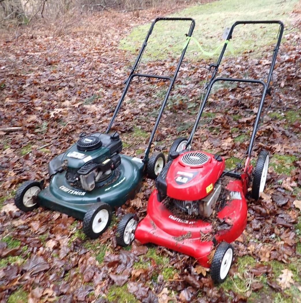 A green Craftsman mower and a red Yard Machines mower sit side-by-side on a lawn.
