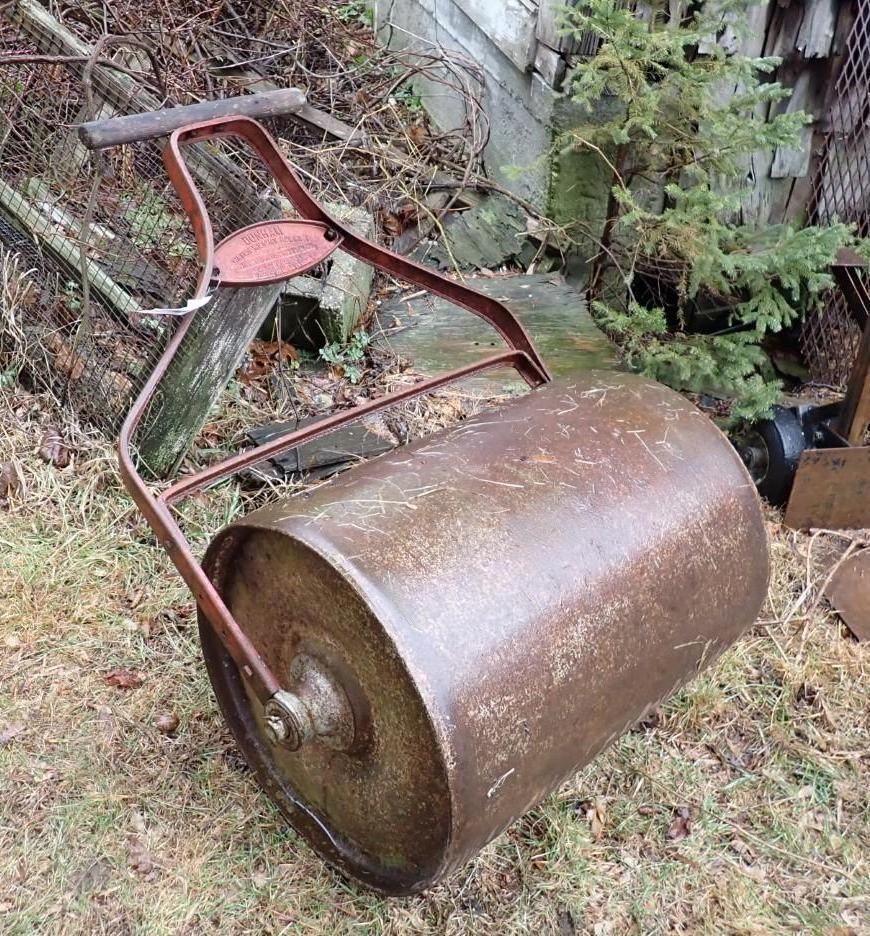 A metal lawn roller with a long handle.