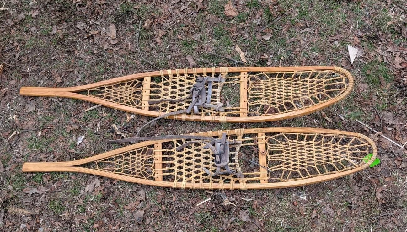 Two traditional wooden-framed snowshoes with laced webbing.