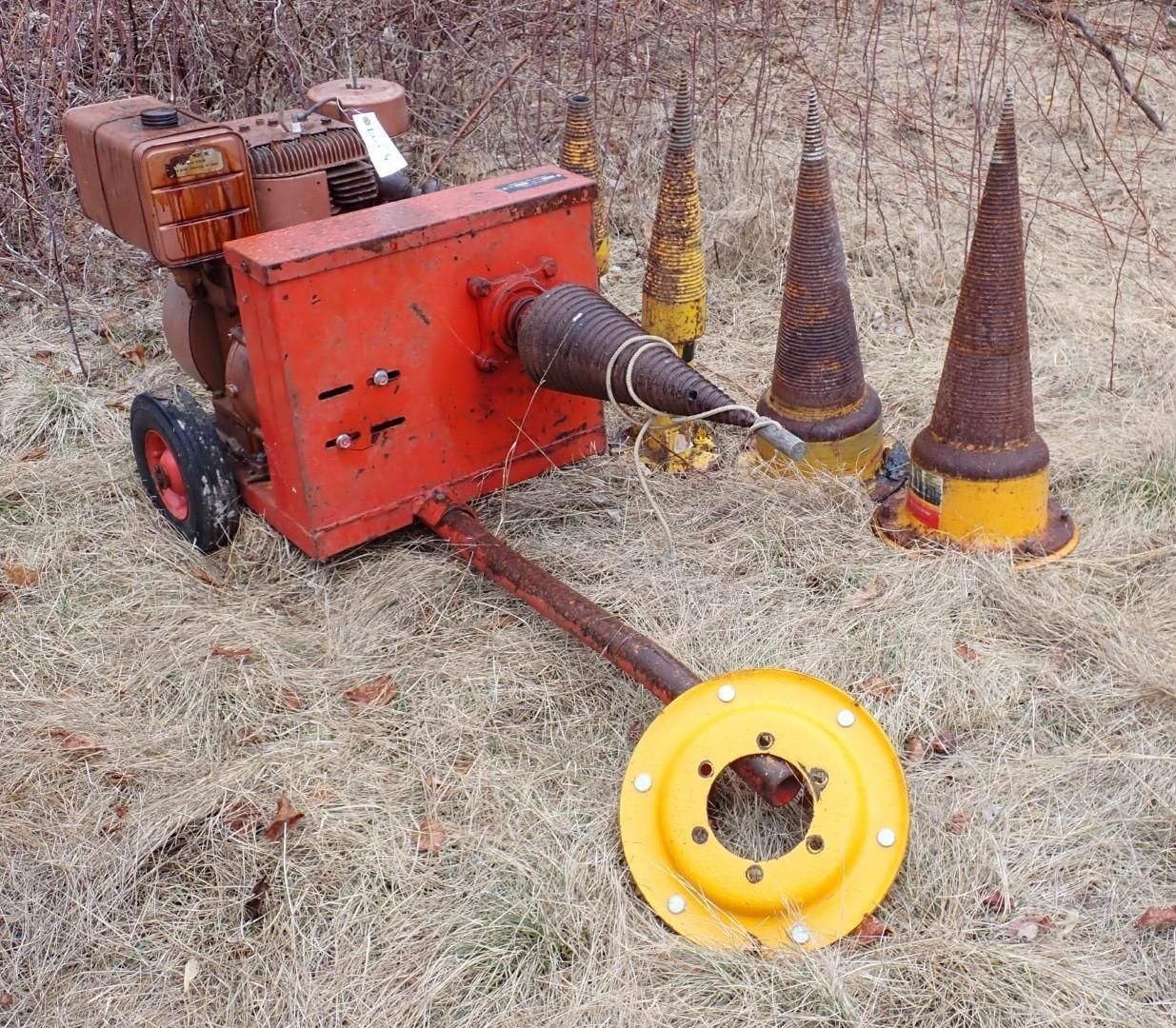A red, engine-powered log splitter with a conical screw and spare yellow metal cones.