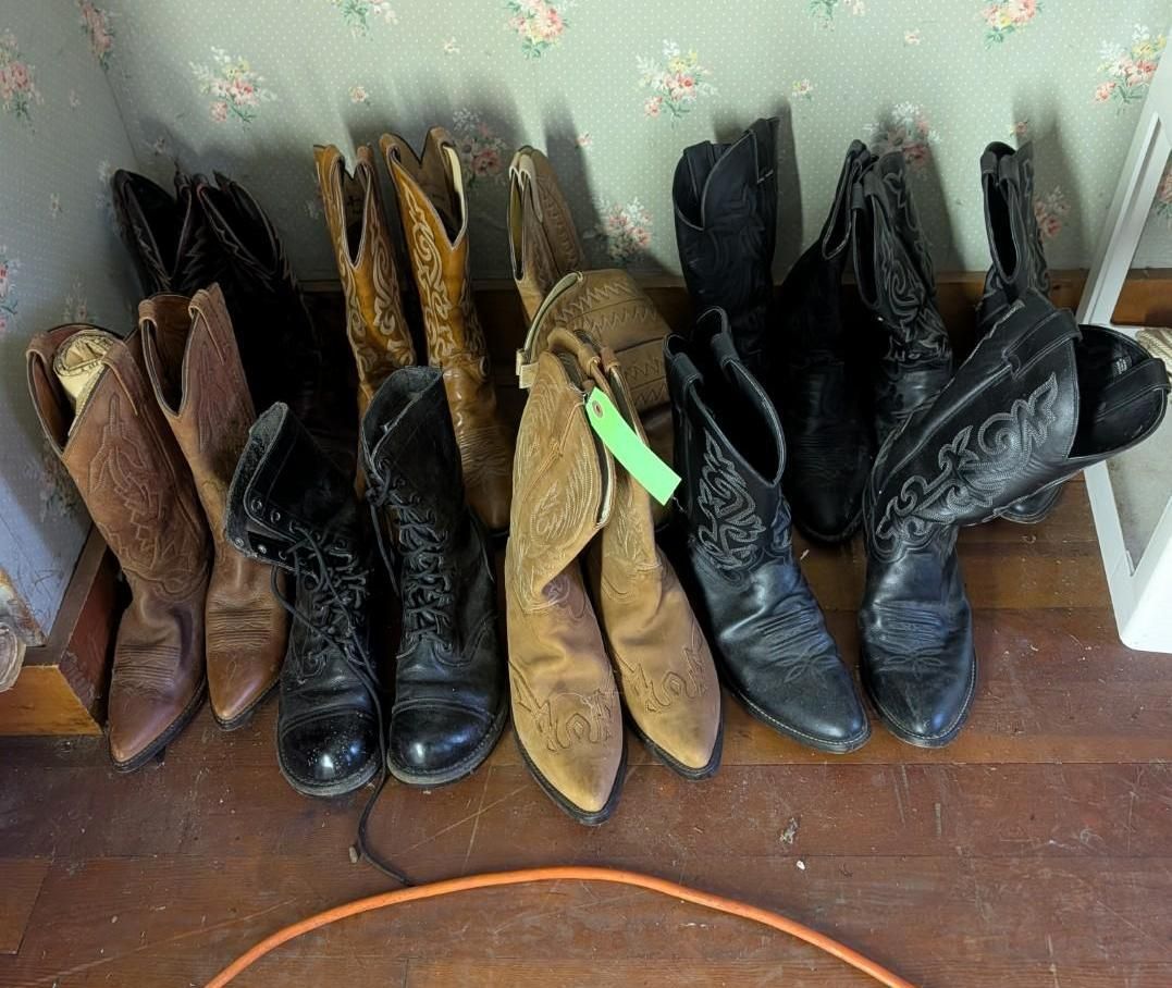 A variety of brown and black leather cowboy boots arranged in a row against a floral-patterned wall on a wooden floor.