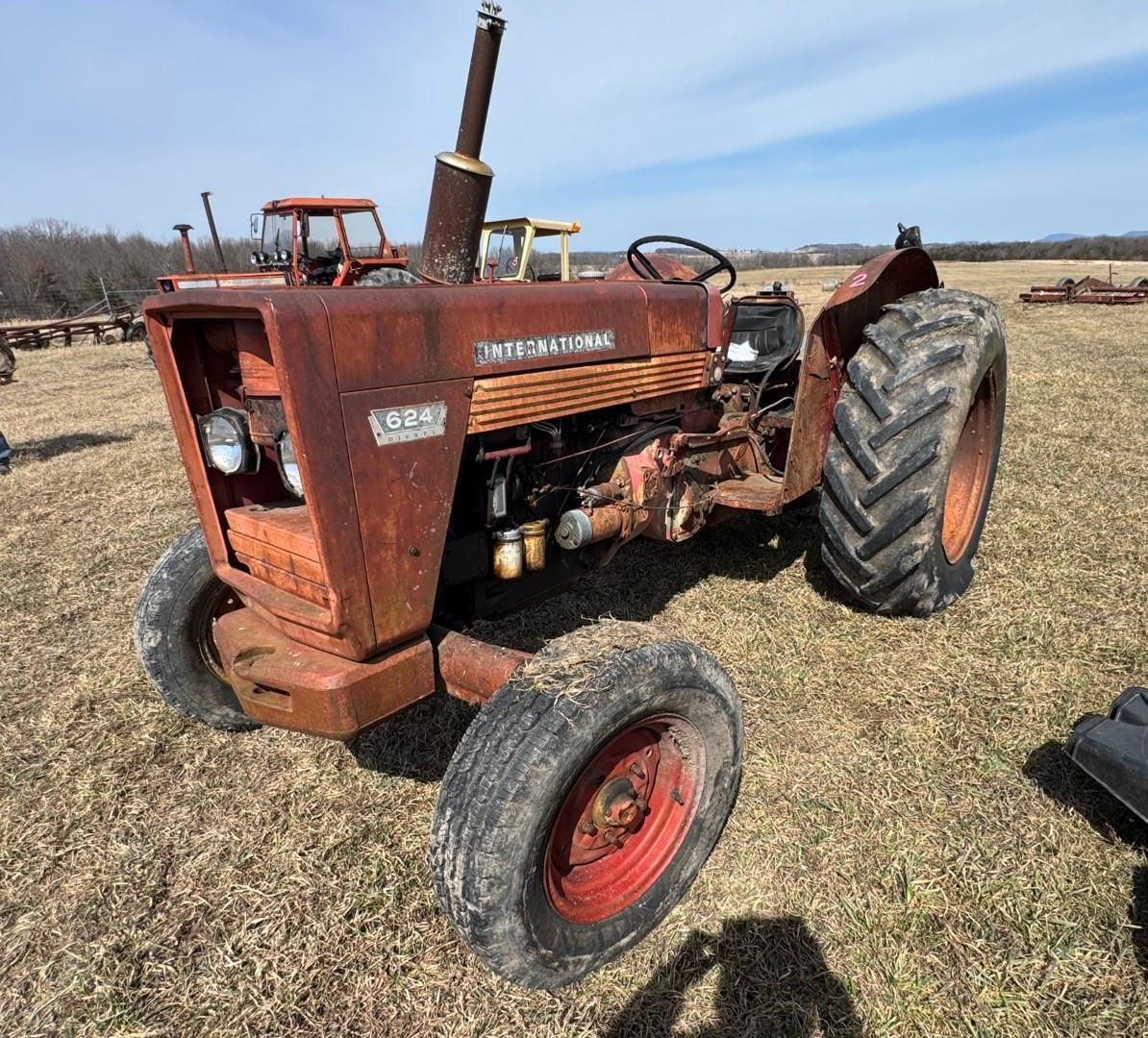 An orange International Harvester tractor parked in a field under a clear blue sky.