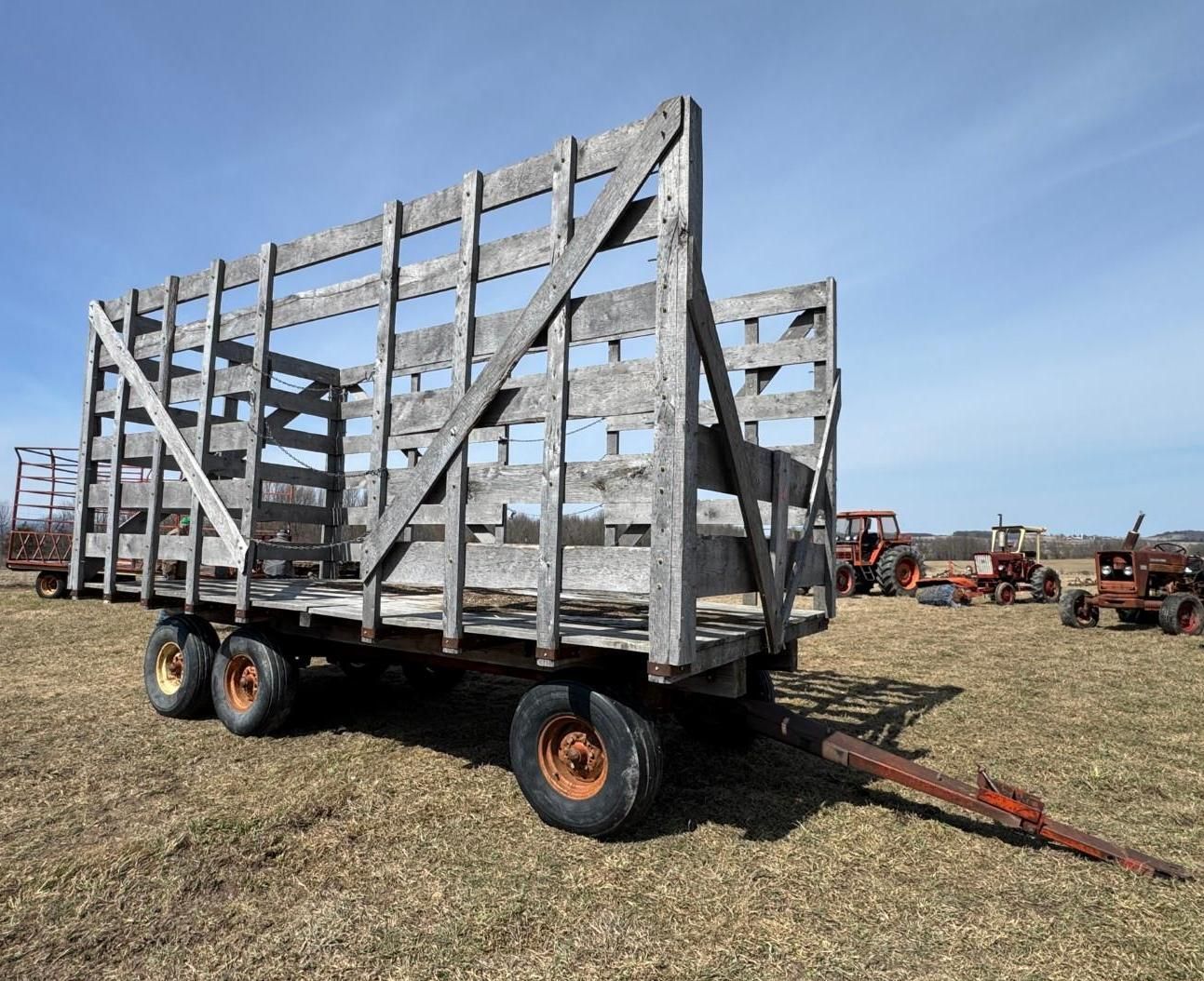 A wooden farm wagon with high slatted sides sits in an open field.