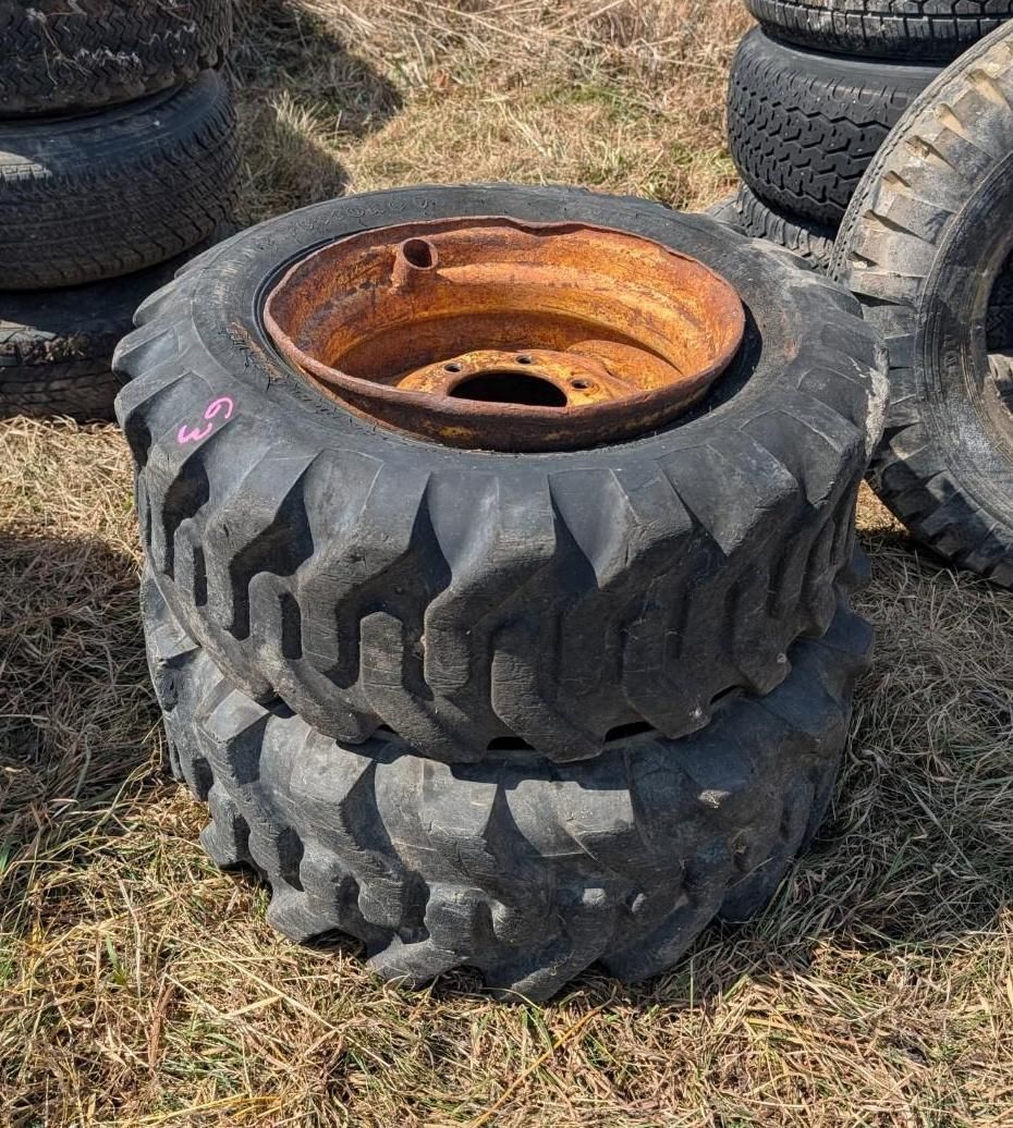 A stack of two rugged off-road tires with a metal rim resting on the grass.