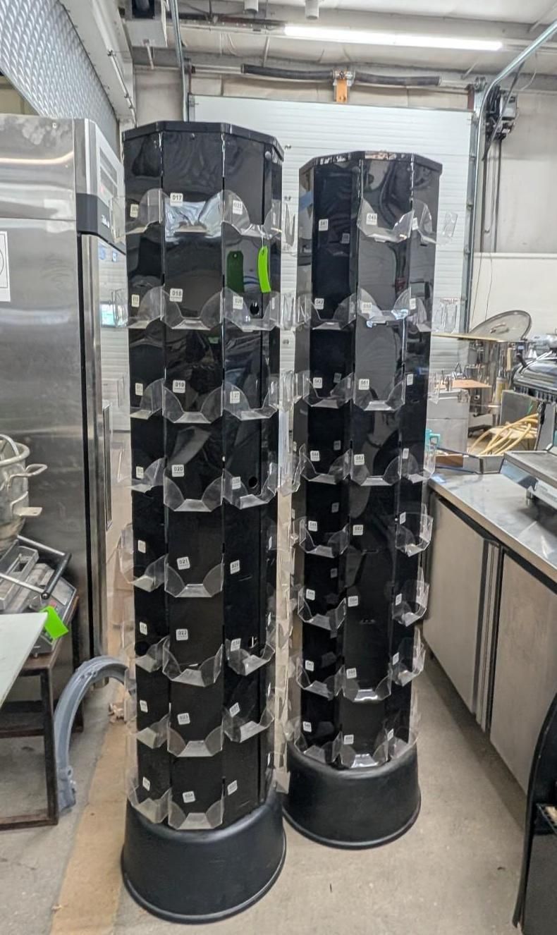 Two tall black cylindrical racks filled with metal parts in an industrial workshop