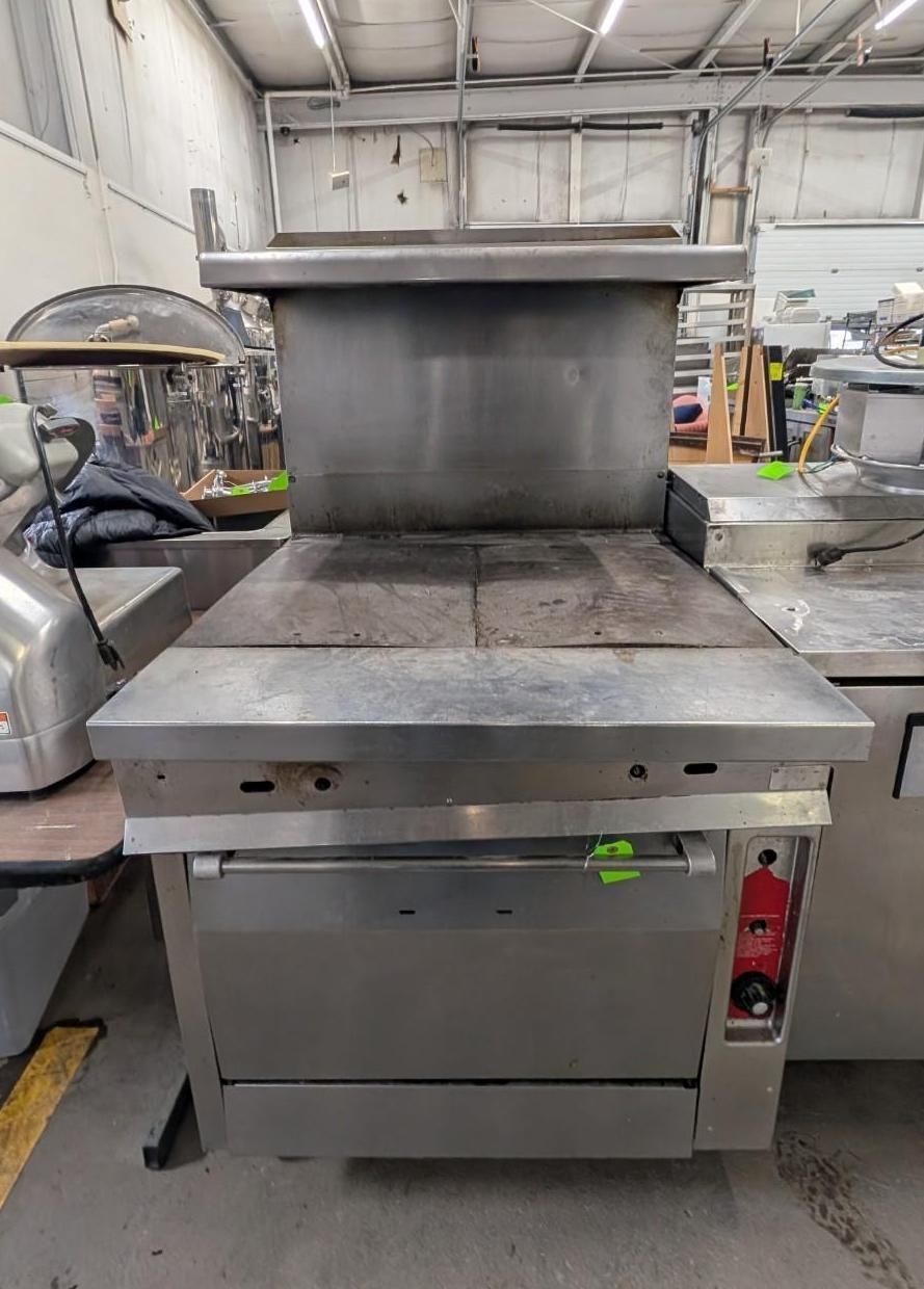 Stainless steel commercial kitchen range with flat griddle and backsplash in a restaurant kitchen