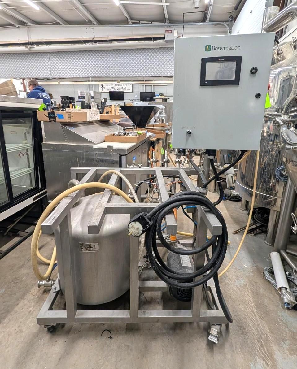 Industrial machine with stainless tank, hoses, and control panel in a workshop