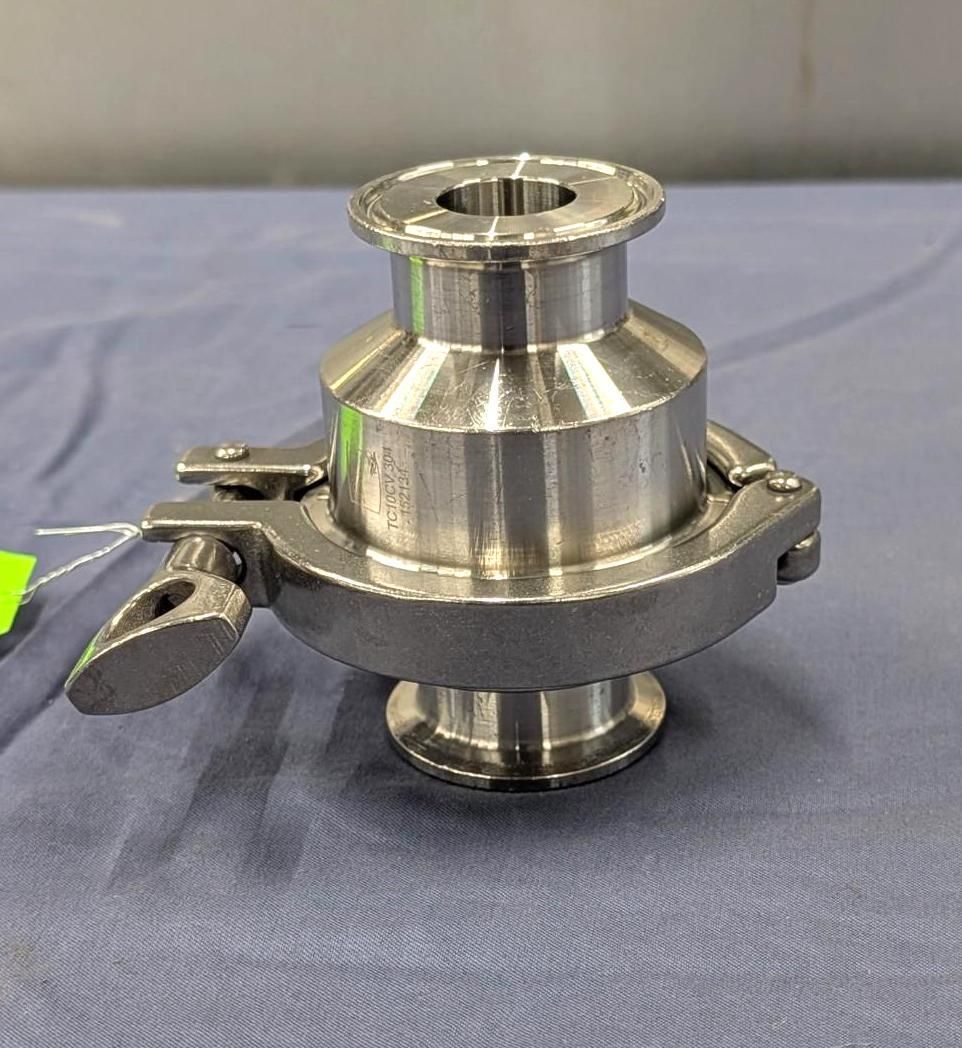 Stainless steel industrial valve component on a blue cloth background