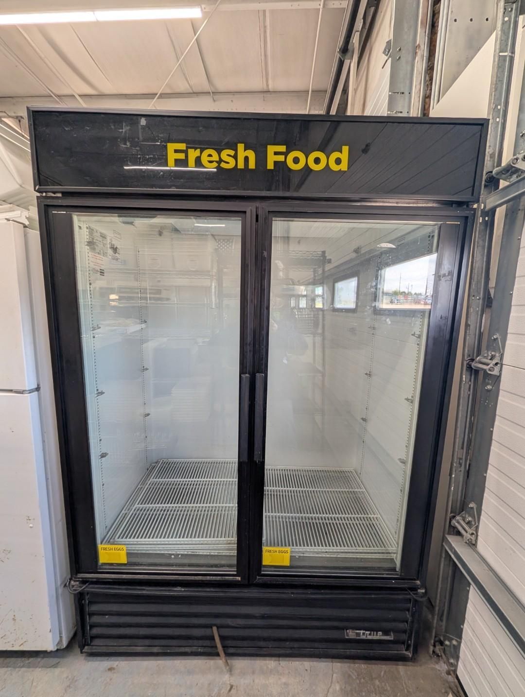 Empty glass-door beverage cooler labeled “Fresh Food” in a store.