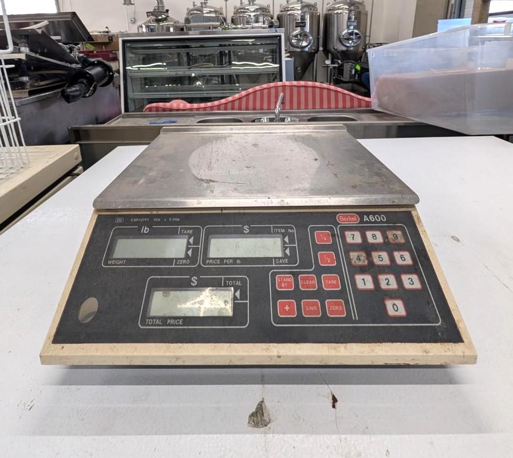 Industrial scale with red and gray buttons on a workbench in a factory setting