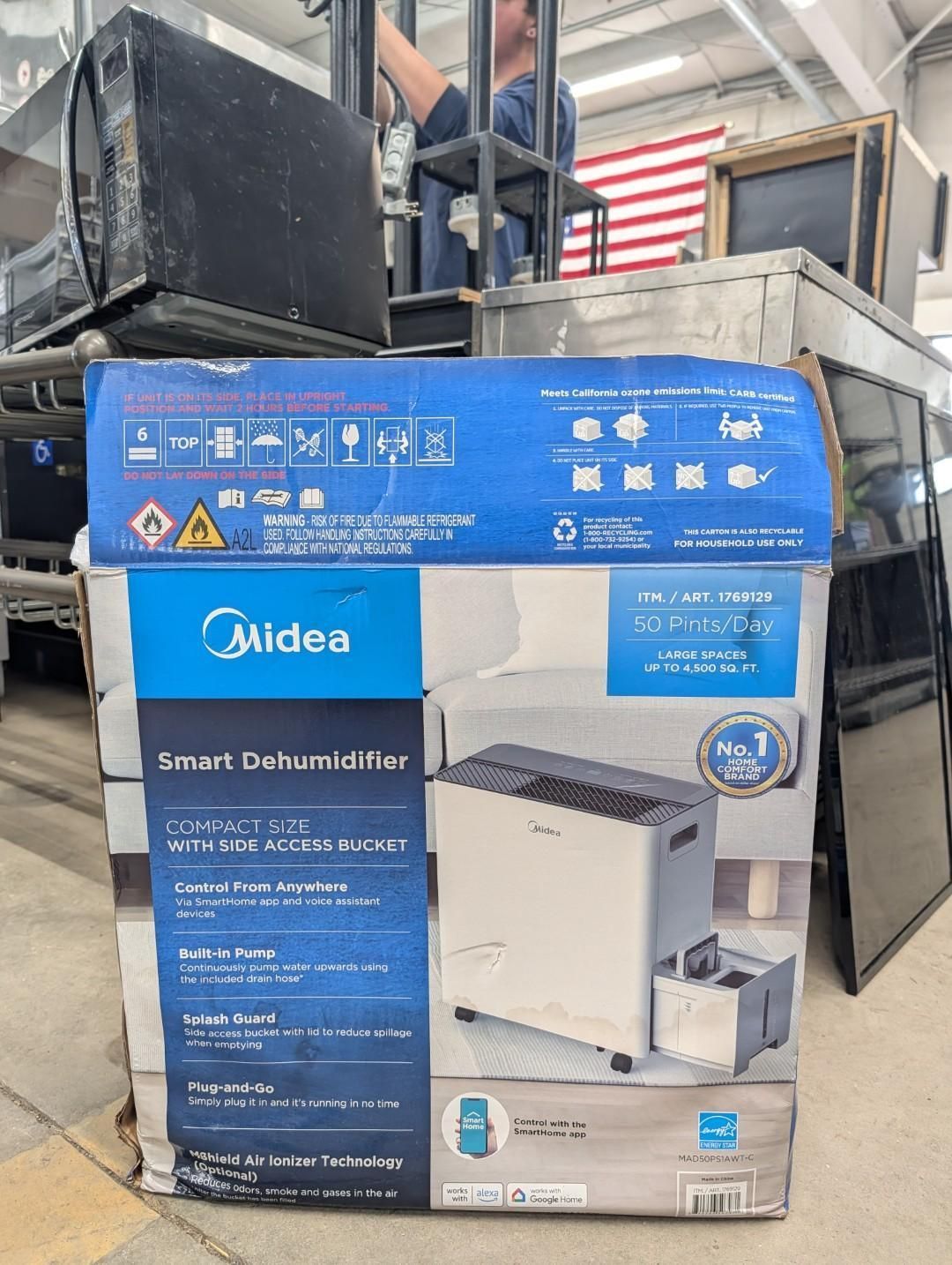 Midea dishwasher box on a warehouse pallet, blue and white packaging with product image and specs