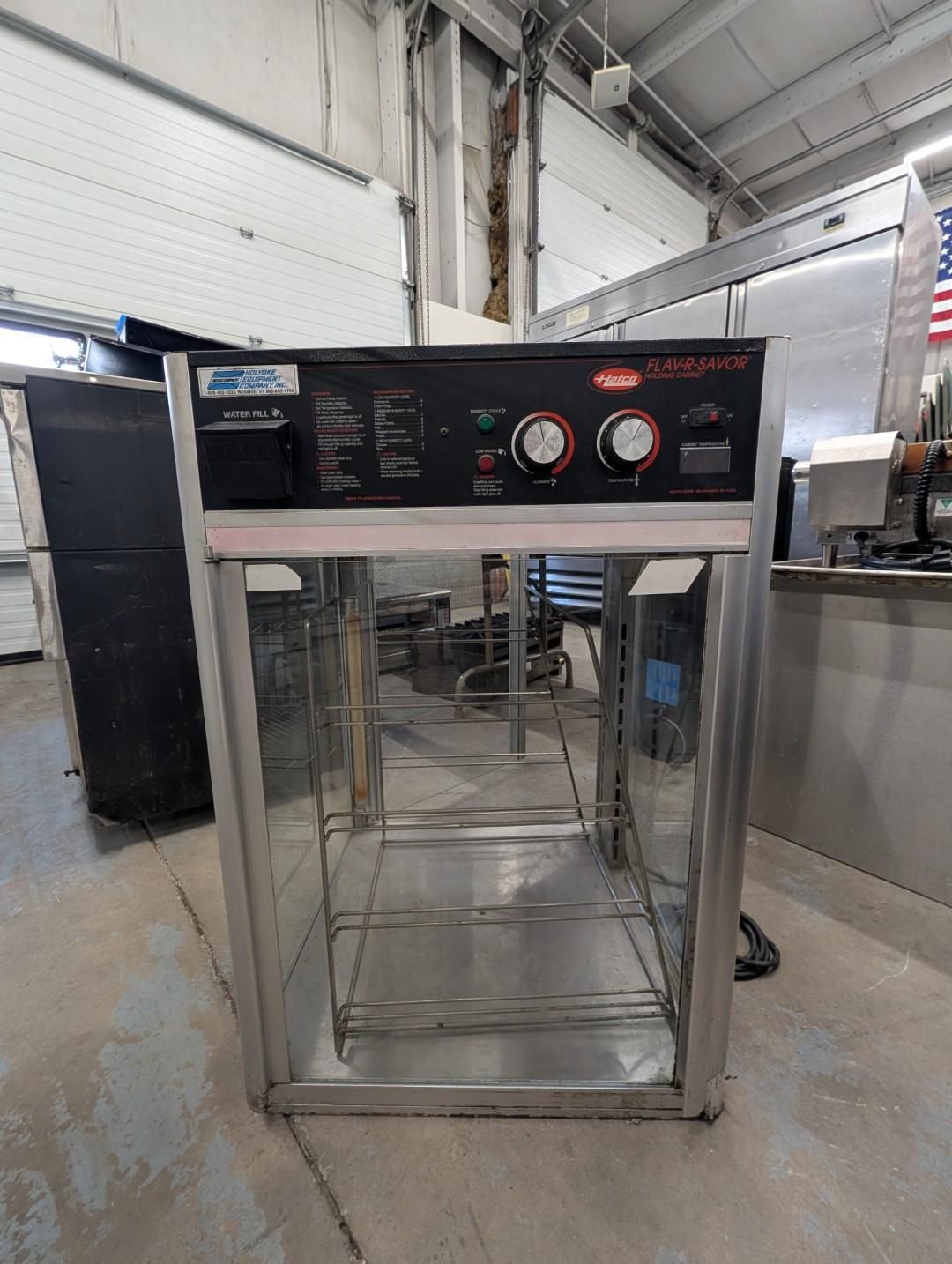 Industrial metal cabinet with clear front door and control panel in a warehouse setting
