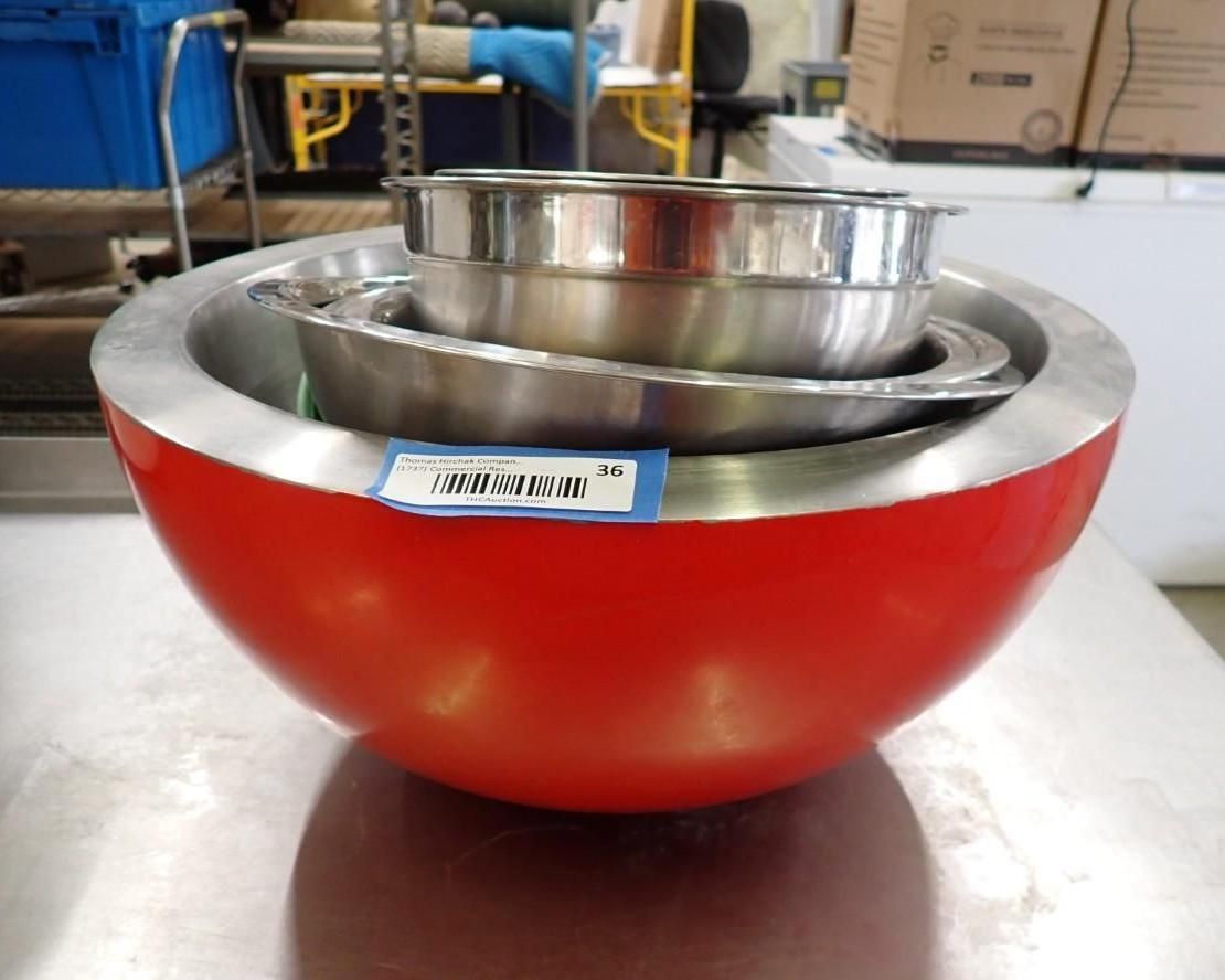 Red and stainless-steel industrial bowl with nested metal inserts on a workbench in a workshop