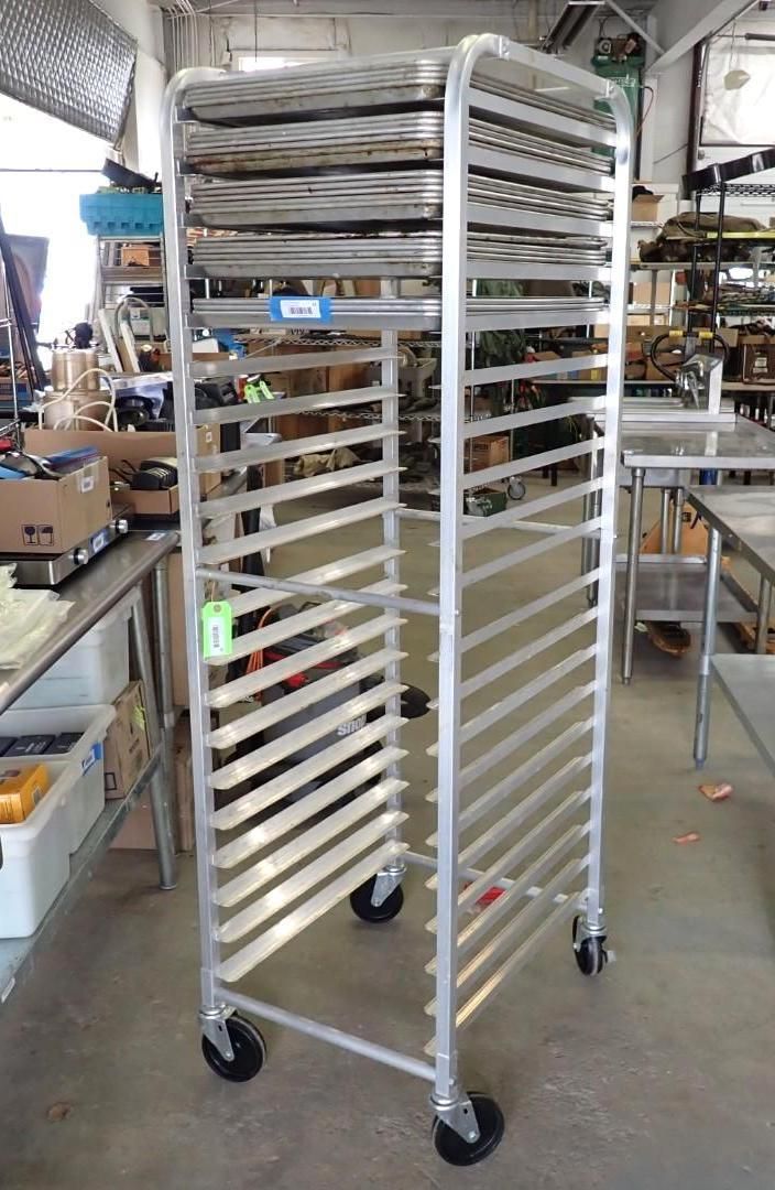 Tall metal bakery rack with shelves and wheels in a workshop or kitchen storage area
