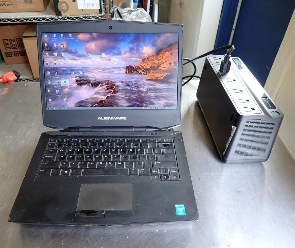 Black Alienware laptop on a desk beside a small white desktop tower.