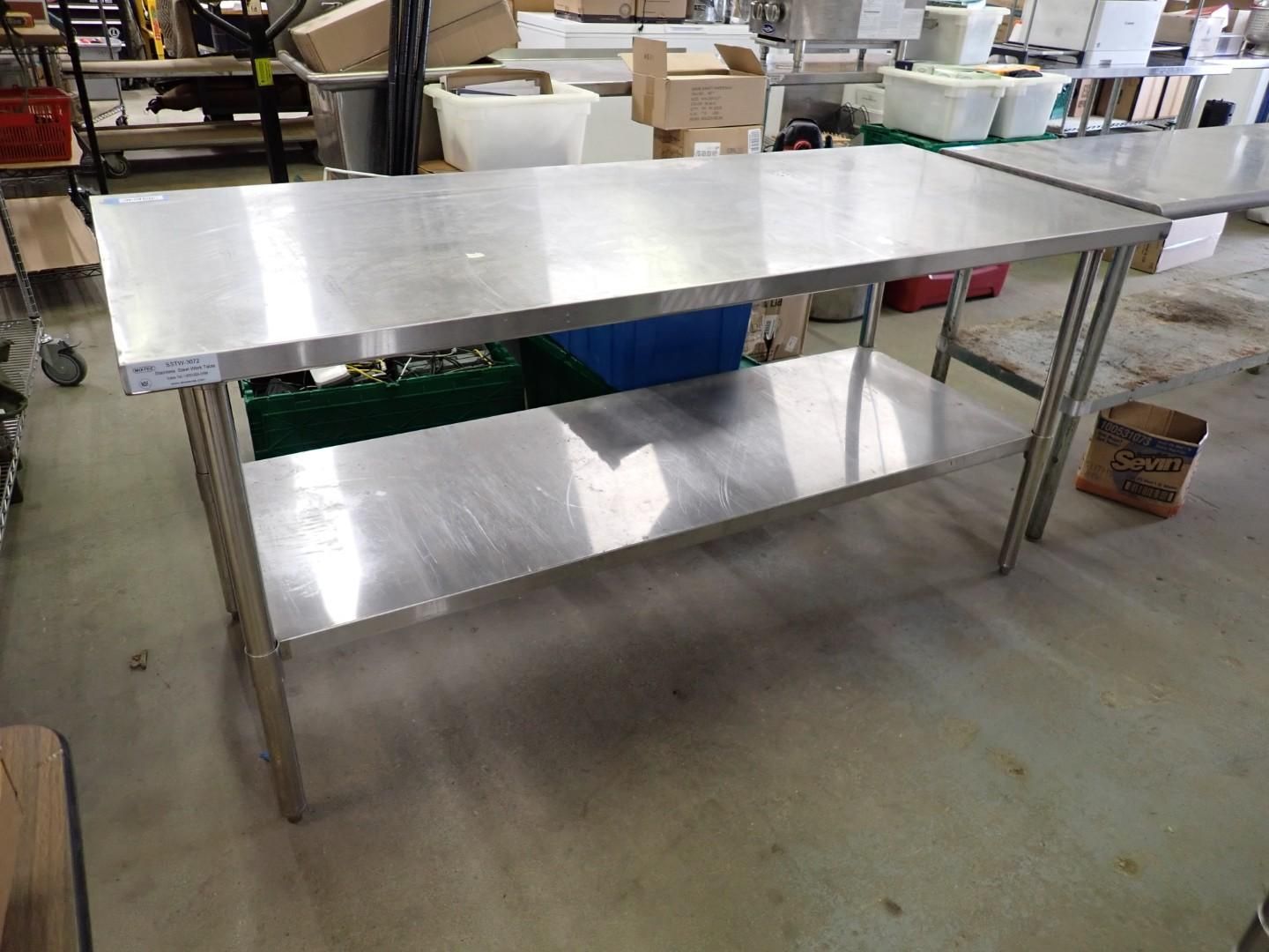 Stainless steel worktable with a lower shelf in a workshop or kitchen area.