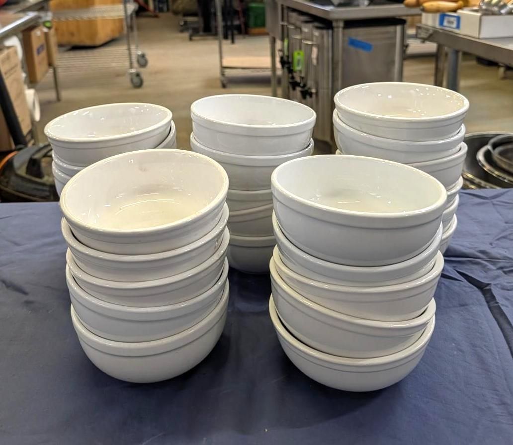 Stacks of white ceramic bowls on a blue tablecloth in a kitchen or dining area