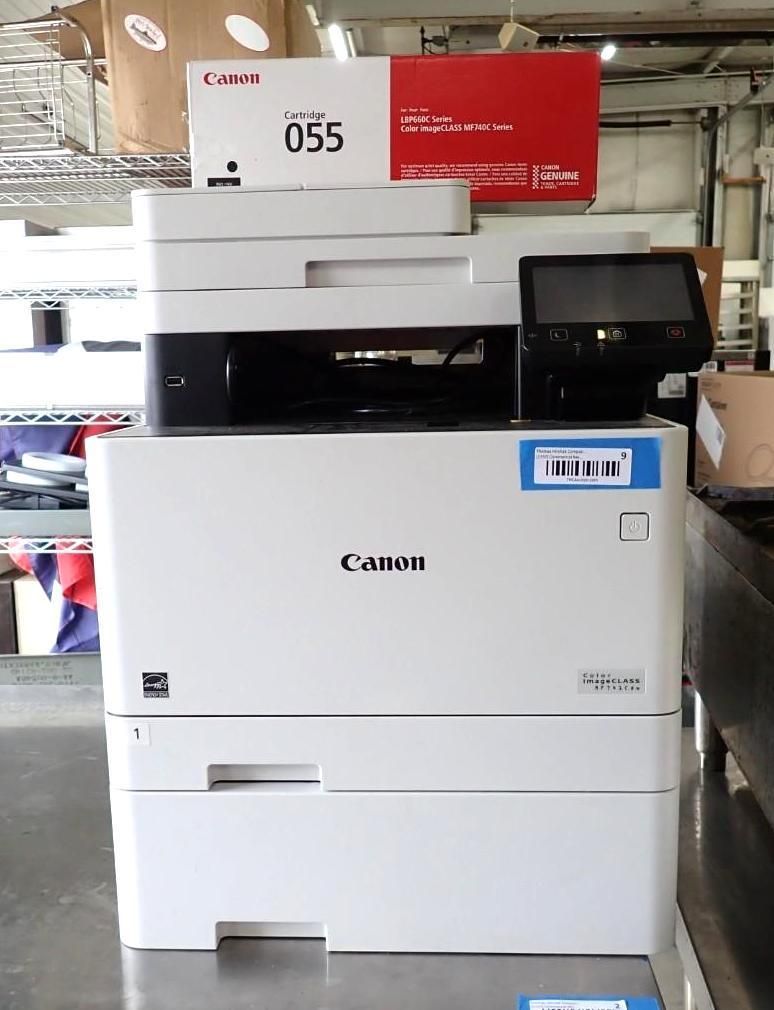 Canon office printer/copier with touchscreen display and paper tray in a warehouse setting
