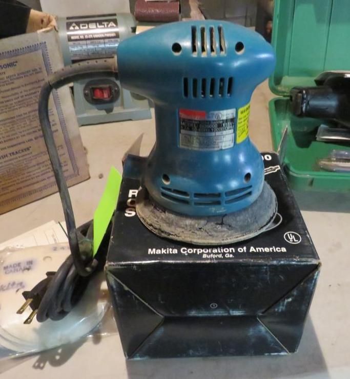 Blue Makita random orbit sander on top of its black box.