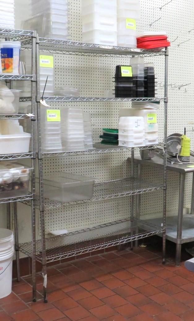 Metal shelving unit holding containers and supplies in a commercial kitchen, set against a white wall.