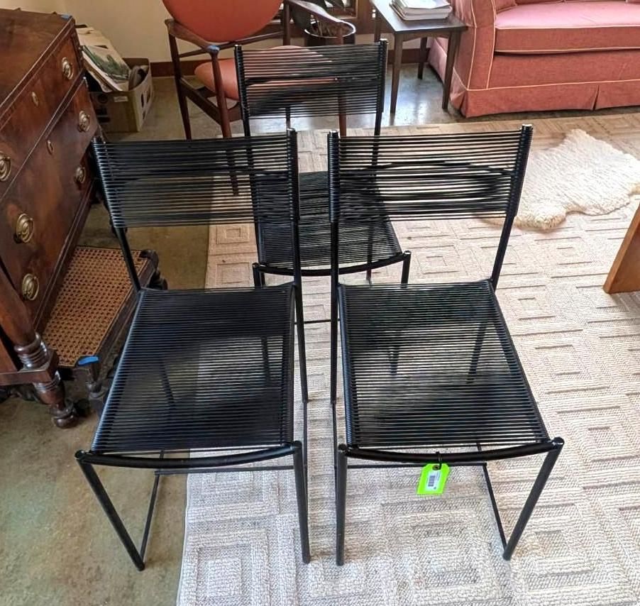 Two black chairs with thin metal frames and seats and backs made of horizontal black cording, standing on a rug.