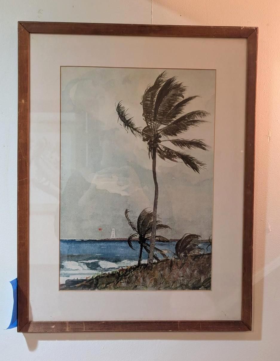 A framed watercolor painting of palm trees leaning in the wind on a beach with blue water and white-capped waves.