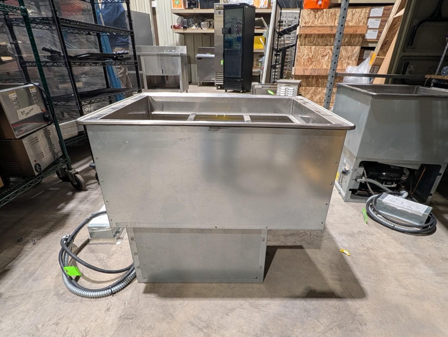 Stainless steel industrial sink or tank on a warehouse floor