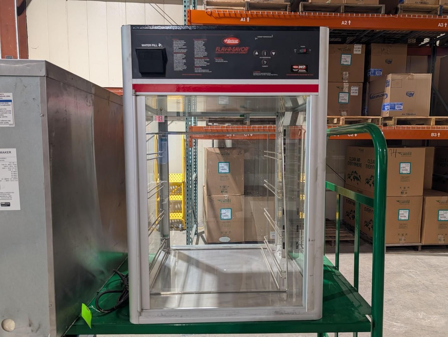 Commercial food warmer with glass doors in a warehouse aisle