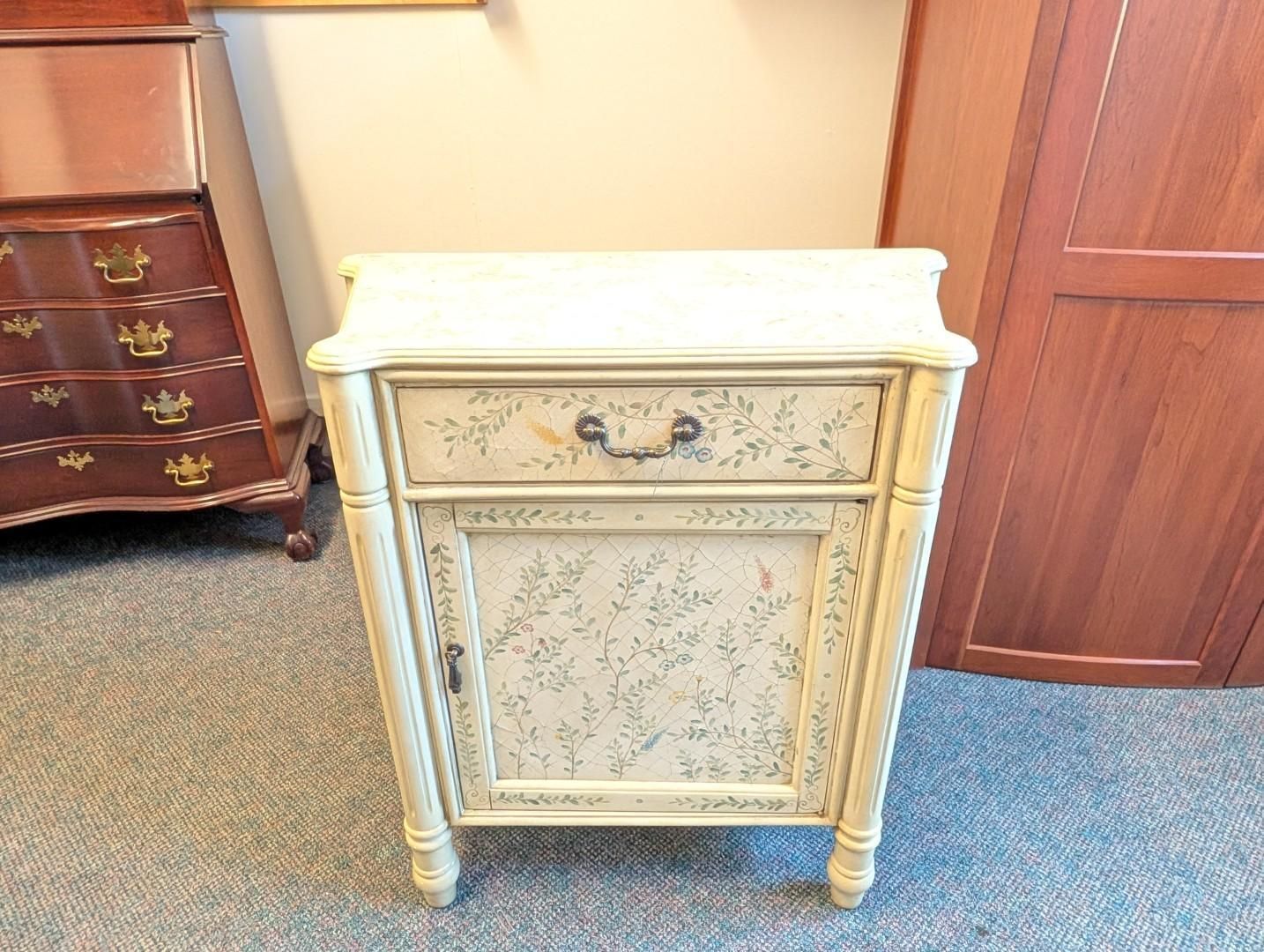 Cream-colored vintage cabinet with floral panel and brass handles