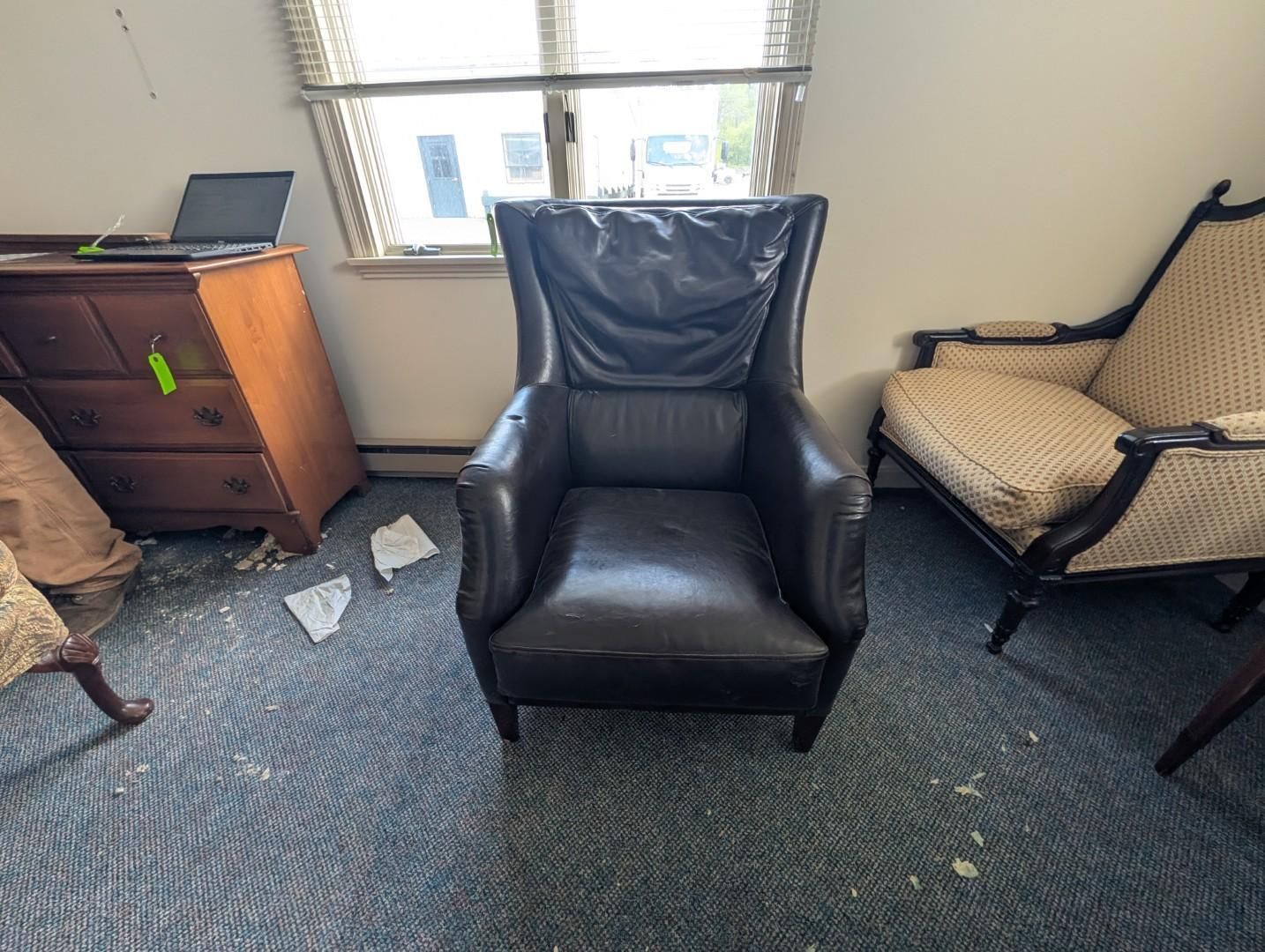 black leather armchair, wooden dresser, and beige upholstered chair