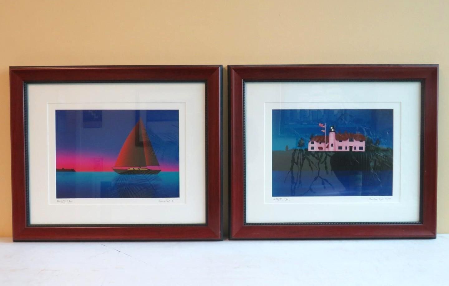 Two framed prints: sailboat at sunset, pink building on a cliff, both with blue and purple tones.