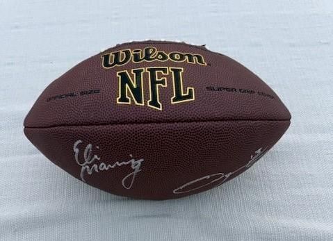 Brown Wilson NFL football with Eli Manning's signature.