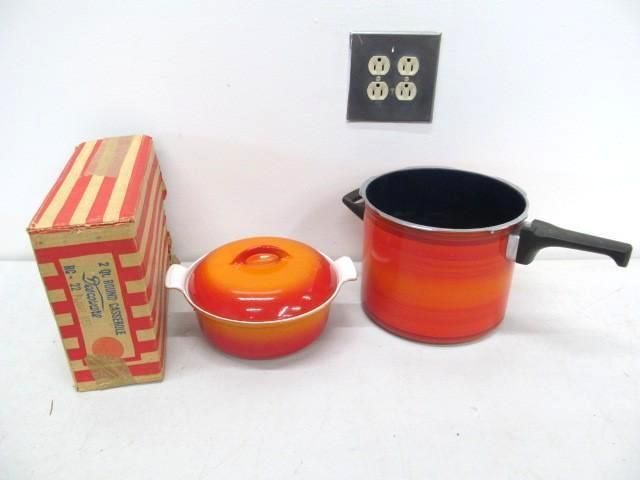 Orange cookware set with box against a white wall and electrical outlet.