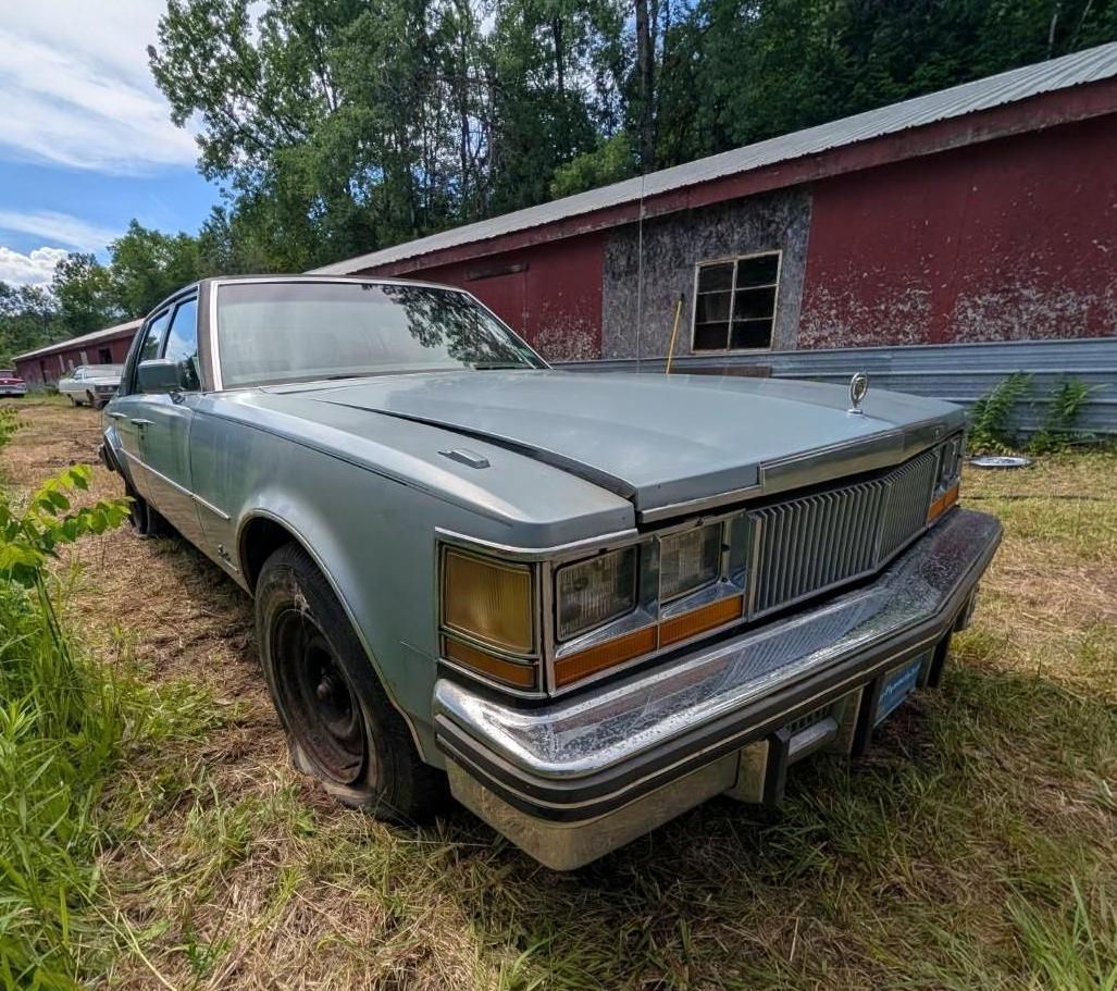 silver sedan beside a red barn in a grassy field