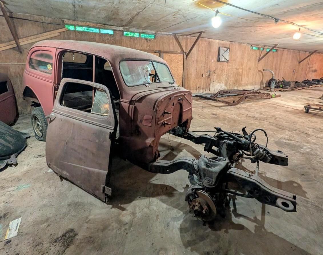 pink vintage car body in a garage, stripped of wheels and engine, on a concrete floor