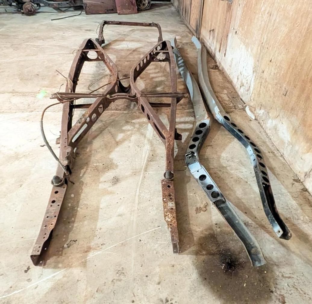 metal frame and two bent bars lying on a concrete floor against a wall.