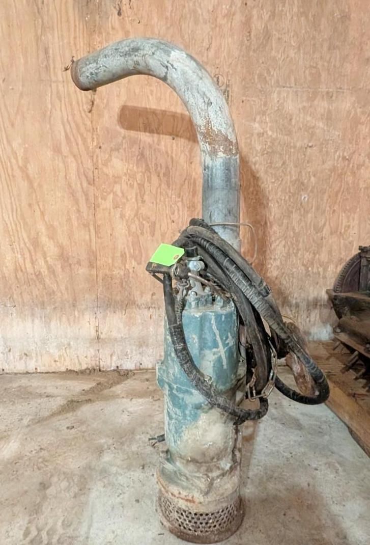blue hand water pump with a coiled hose, standing against a wooden wall.