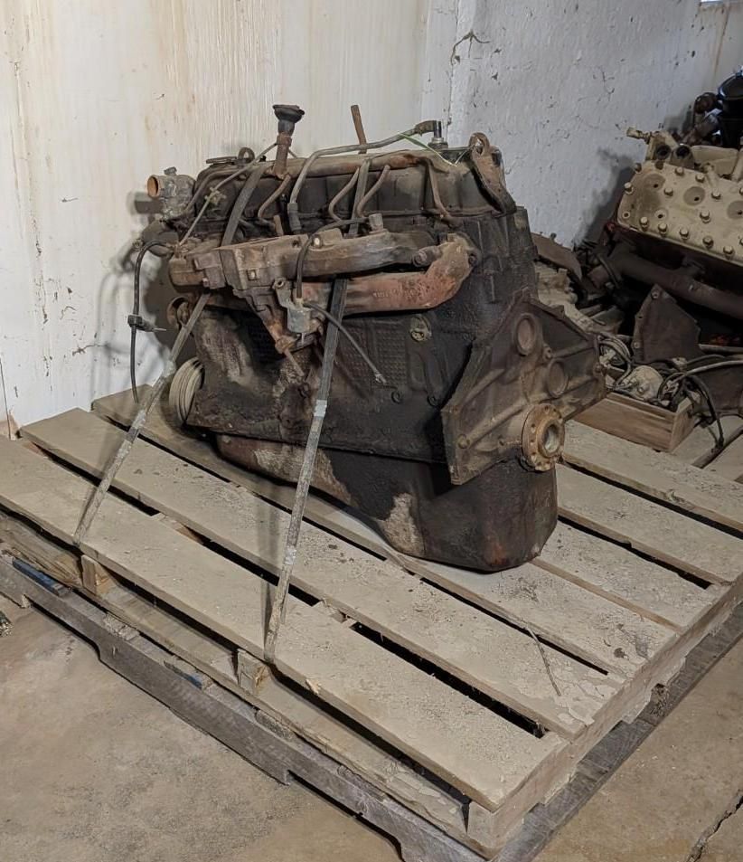 engine or machinery parts strapped on a wooden pallet in a workshop corner
