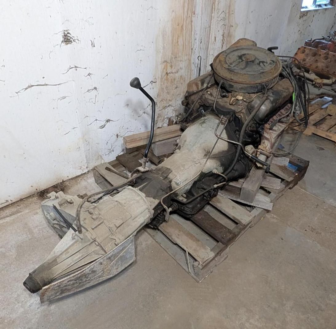 motorcycle frame and parts stacked on wooden pallets against a stained wall.