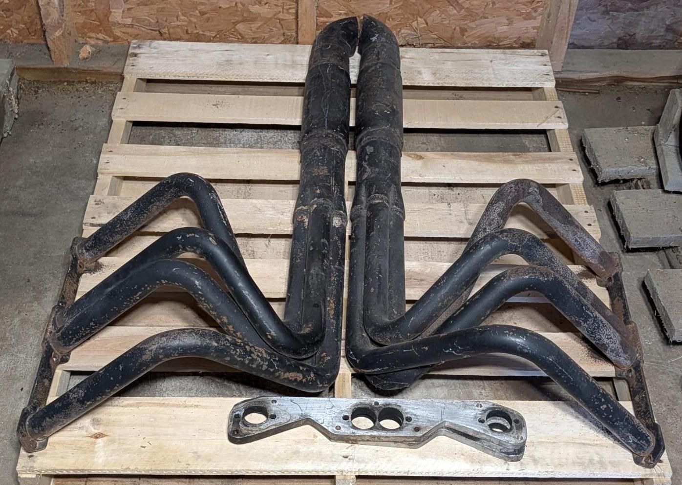 Black metal fireplace tool set on a wooden pallet against a brick wall.