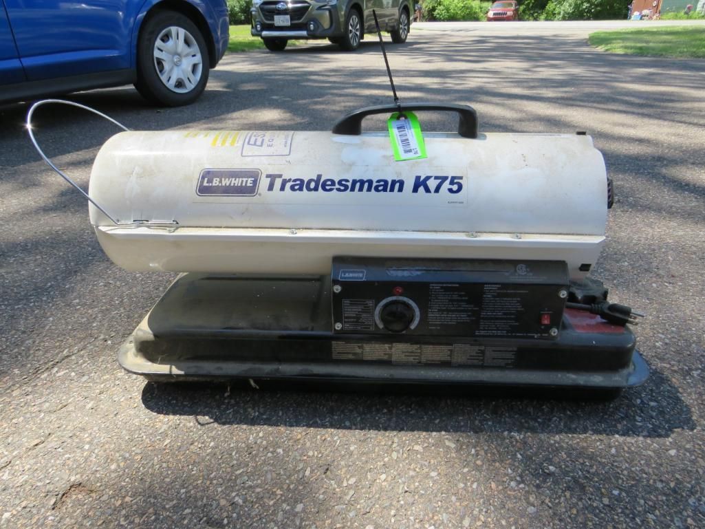 A cylindrical, white L.B. White Tradesman K75 space heater on asphalt with a black control panel.