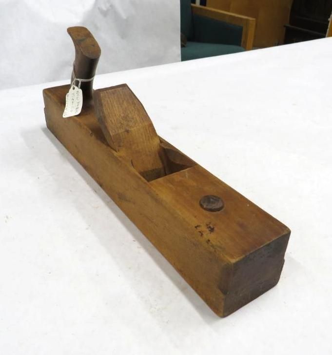 Wooden smoothing plane with a dark handle, on a white surface.