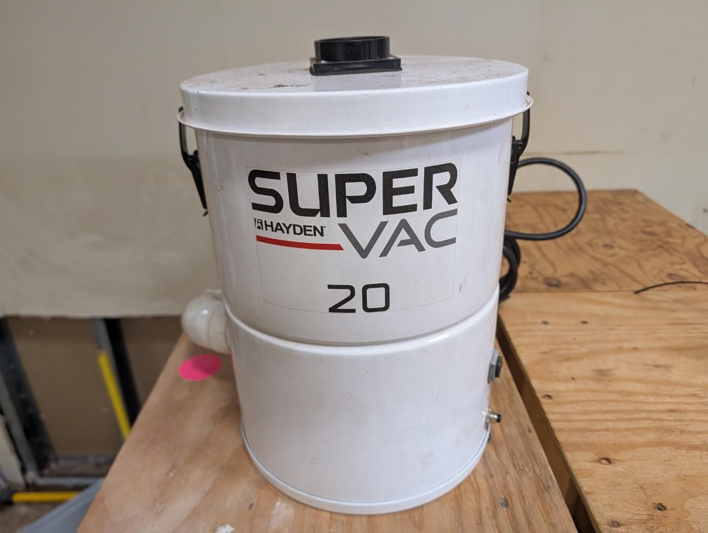 White Super Vac vacuum drum on a wooden workbench, labeled