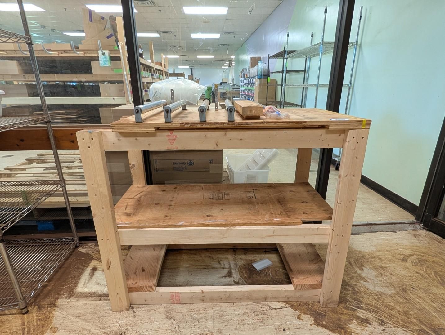 Wooden workbench in a workshop with shelves and a white machine in the background