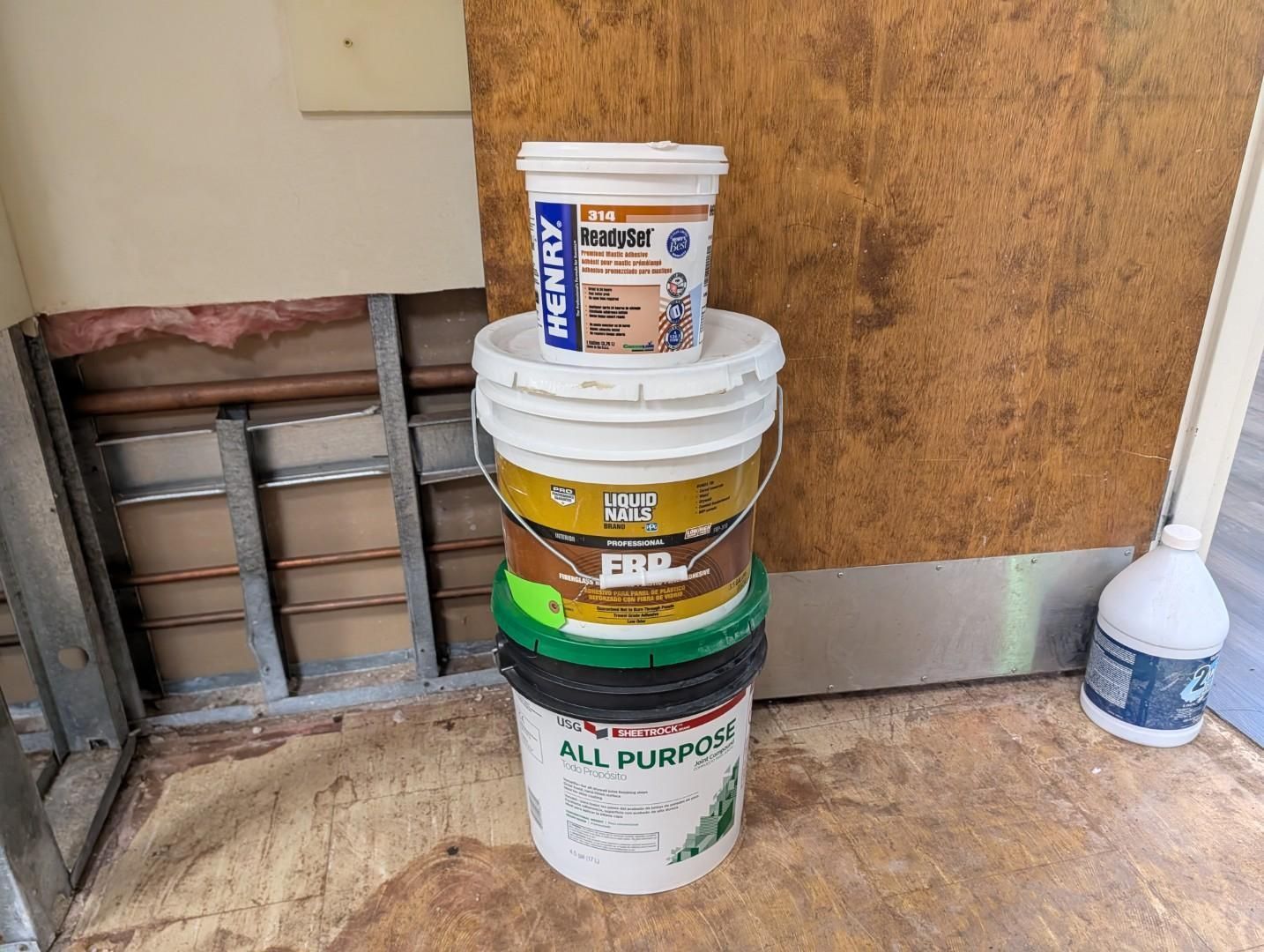 Stack of paint and compound buckets in a room