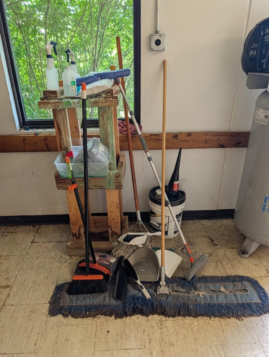 Cleaning tools and supplies on a blue mat beside a window and water cooler in a room