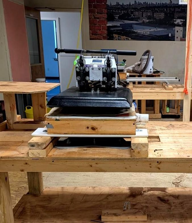 Woodworking shop with a large planer or press mounted on a wooden workbench and pallet base.